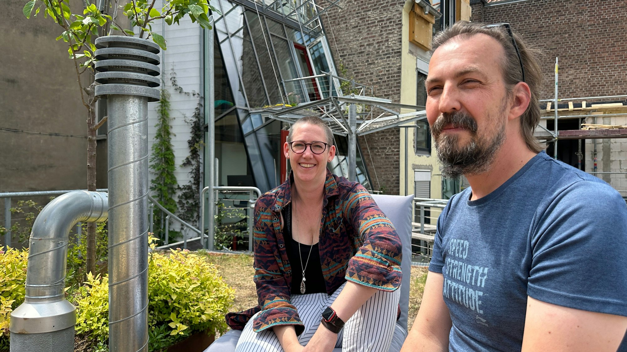 Zwei Leute sitzen auf einer Dachterrasse.