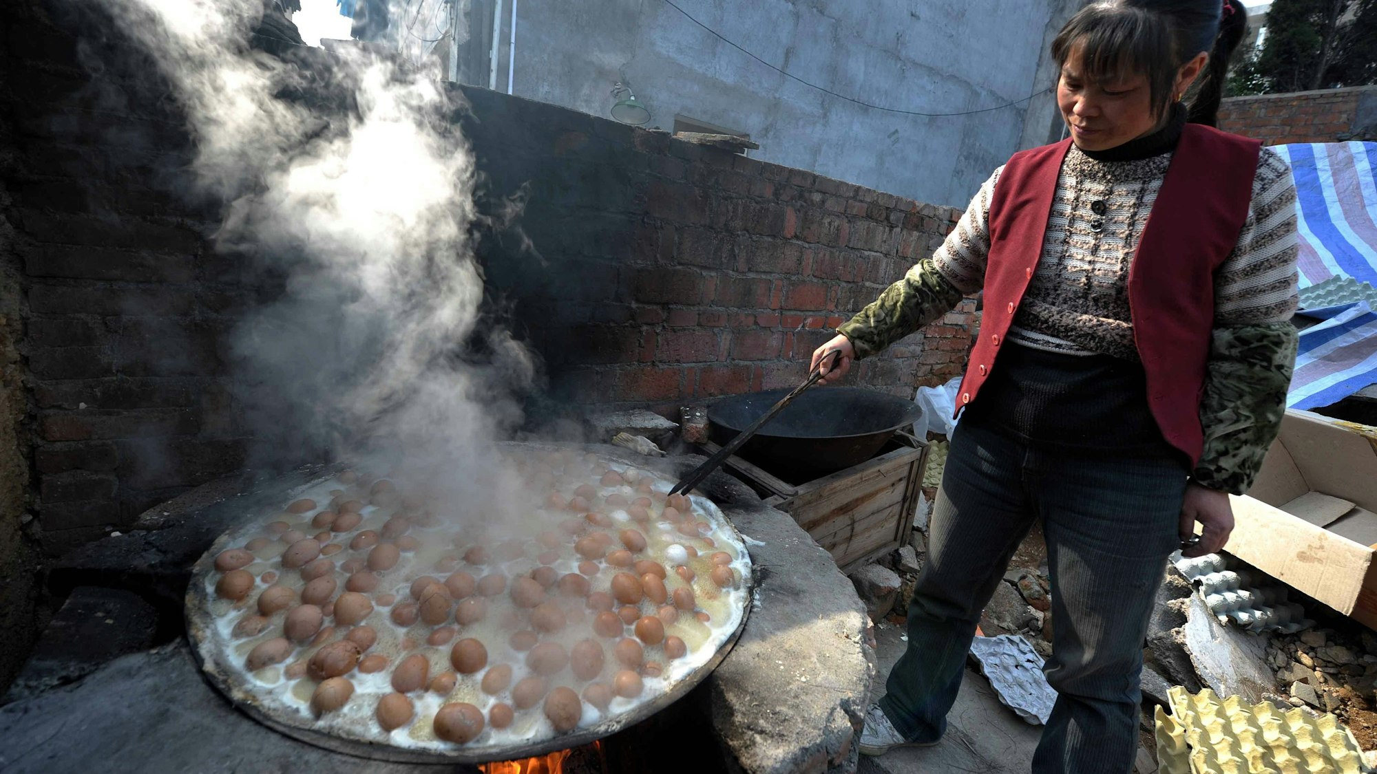 Eine Frau kocht die „Urin-Eier“ in einem großen Behältnis.