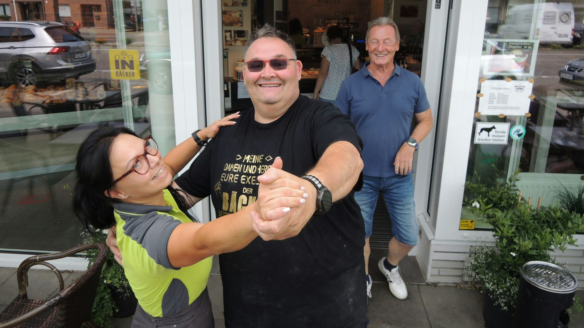 Guido Boveleth und seine Mitarbeiterin Sarah Porwol demonstrieren vor der Bäckereifiliale in Kaster, wie es geht: Wer tanzt, bekommt Brötchen oder Teilchen.