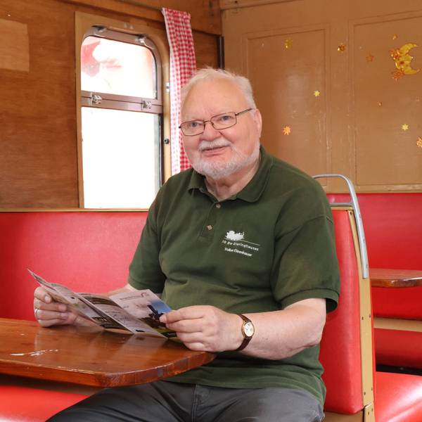 Volker Eisenhauer sitzt an einem Tisch in einem alten Eisenwagenwagon.