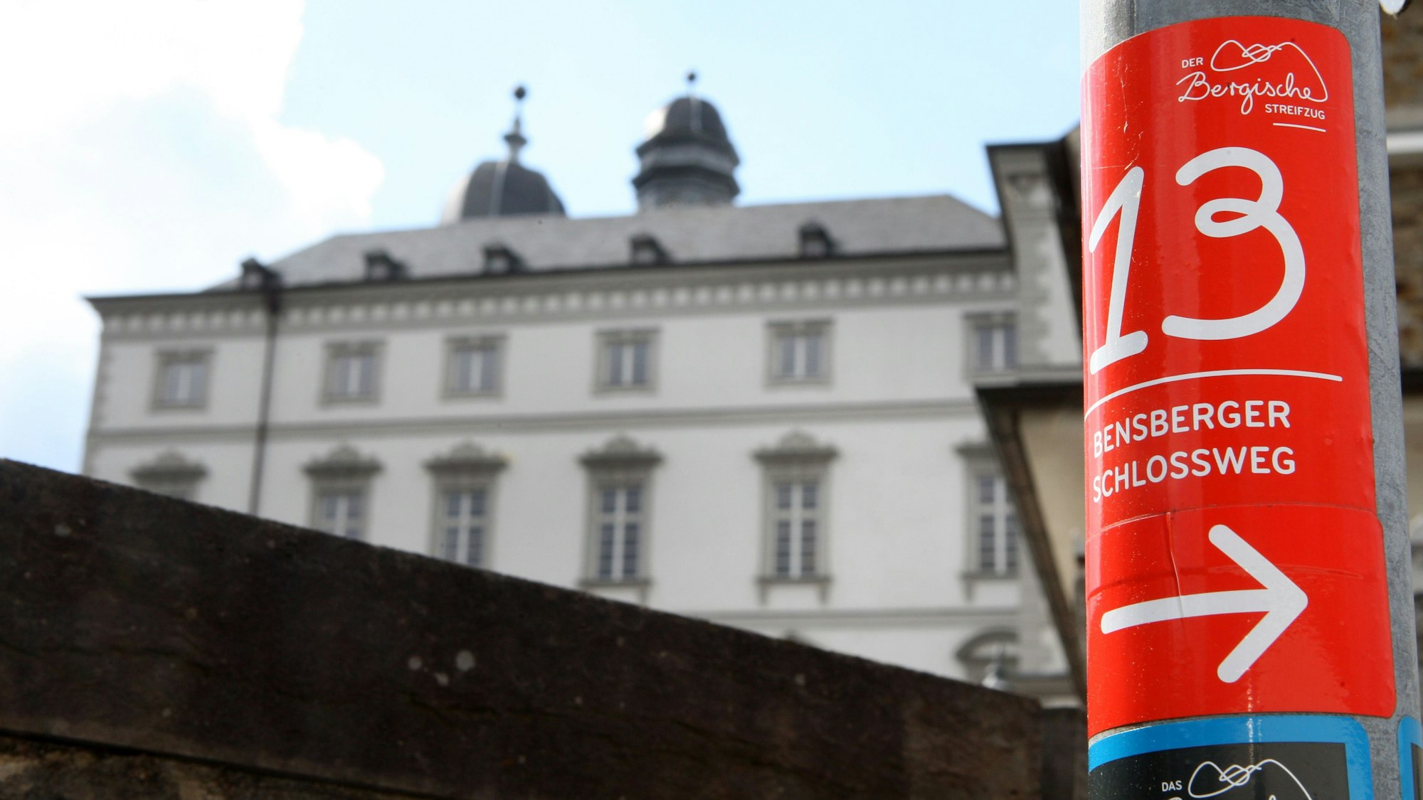 Die Wegemarkierung des Bensberger Schlosswegs klebt an einem Laternenpfahl vor dem Bensberger Barockschloss.