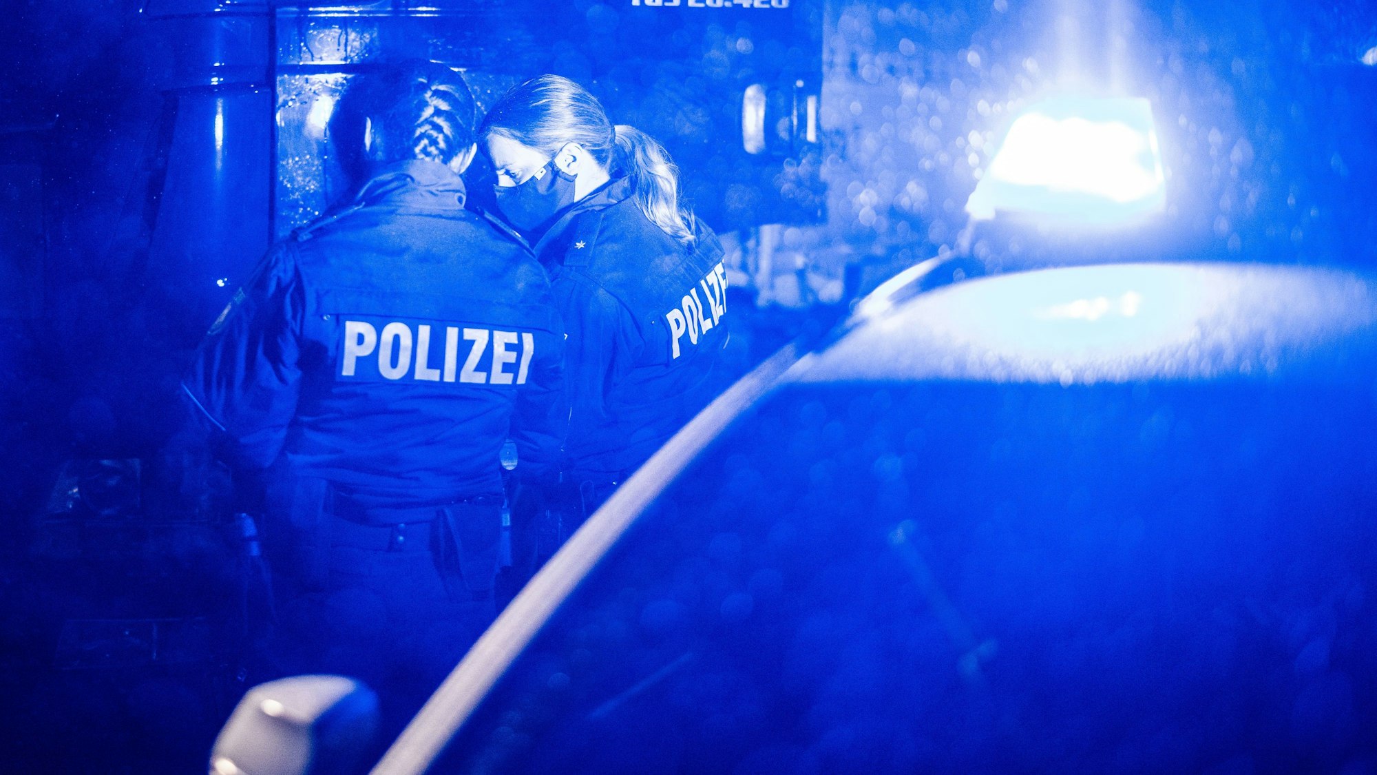 Zwei Polizisten stehen vor einem Auto