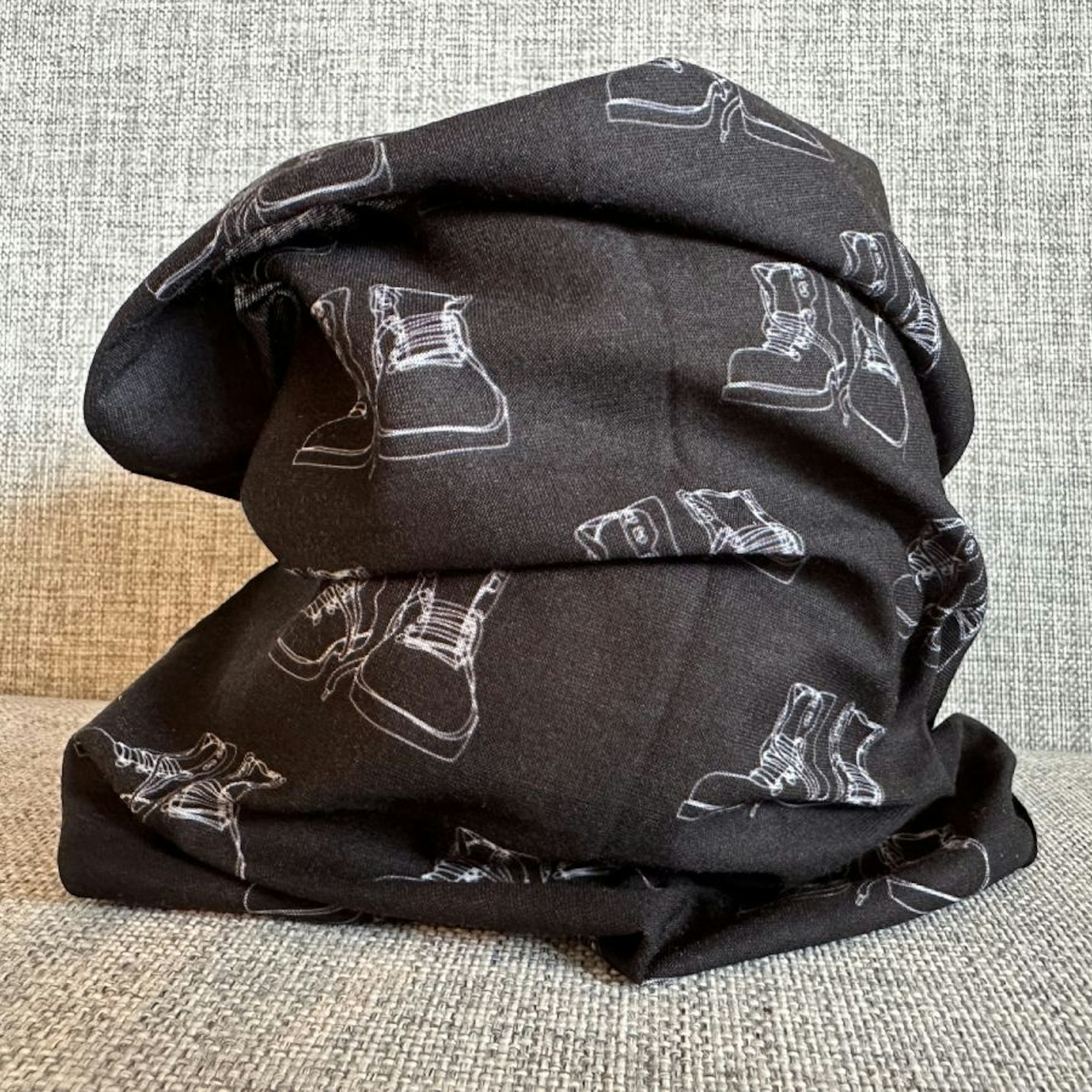 Ein Multifunktionswandertuch des Bergischen Wanderlands liegt auf einer Couch.