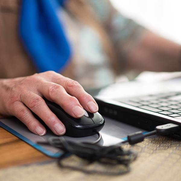 Eine Seniorin sitzt an ihrem Laptop.
