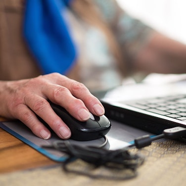 Eine Seniorin sitzt an ihrem Laptop.