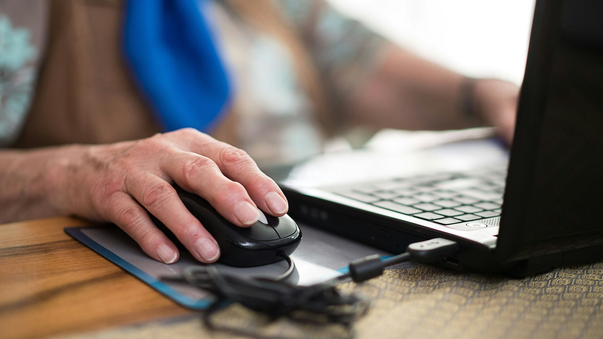 Eine Seniorin sitzt an ihrem Laptop.