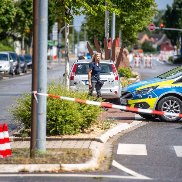 Eine Straße ist mit Flatterband und einem Polizeifahrzeug abgesperrt.
