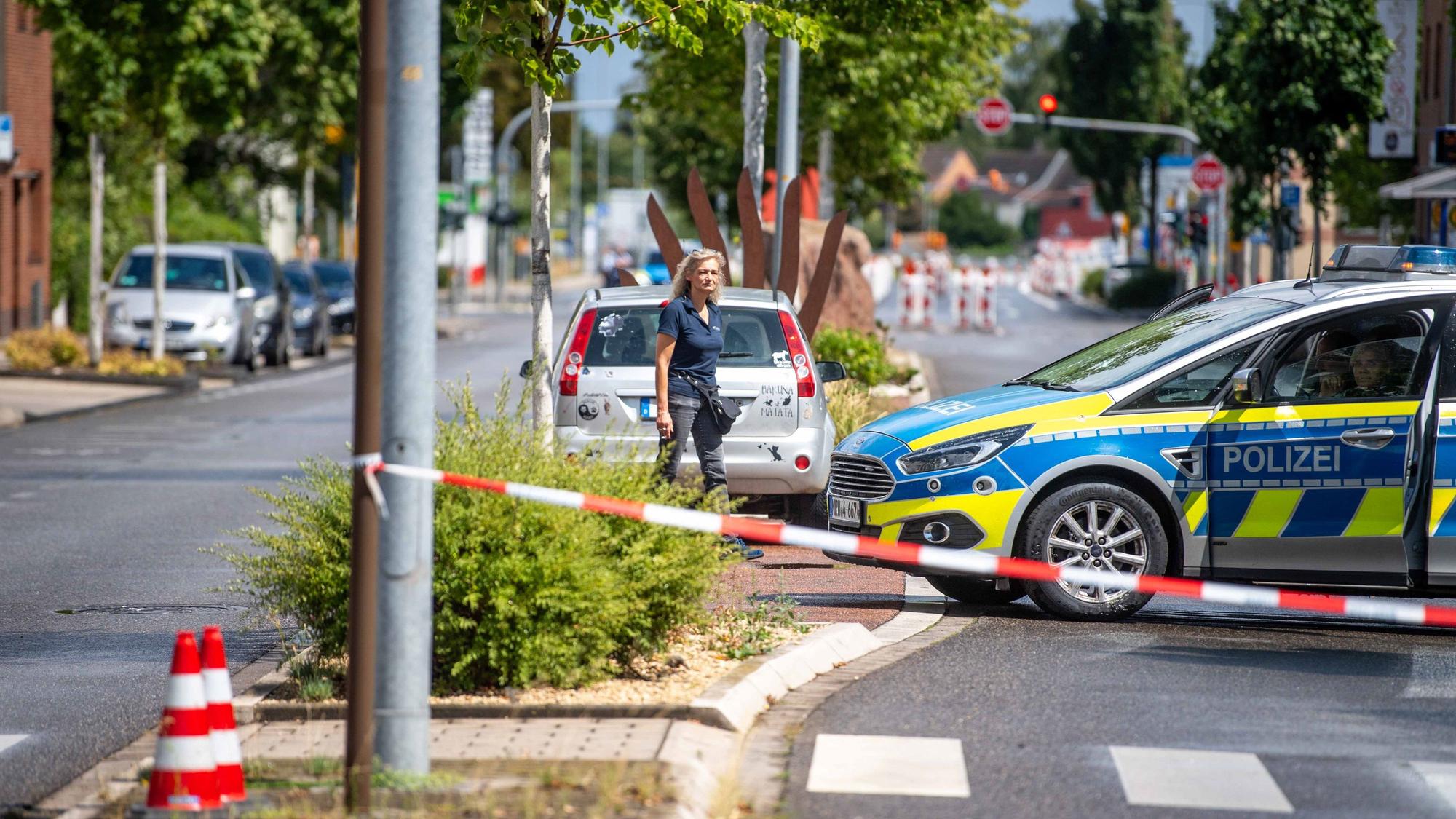 Eine Straße ist mit Flatterband und einem Polizeifahrzeug abgesperrt.