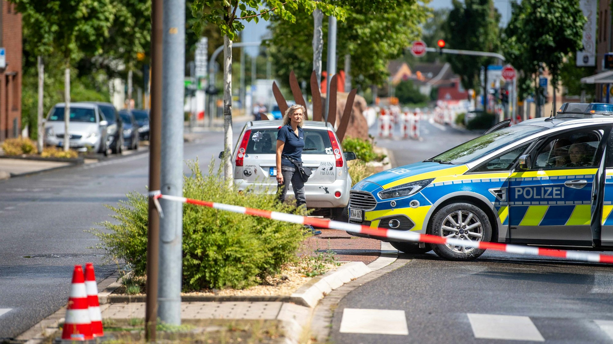 Eine Straße ist mit Flatterband und einem Polizeifahrzeug abgesperrt.