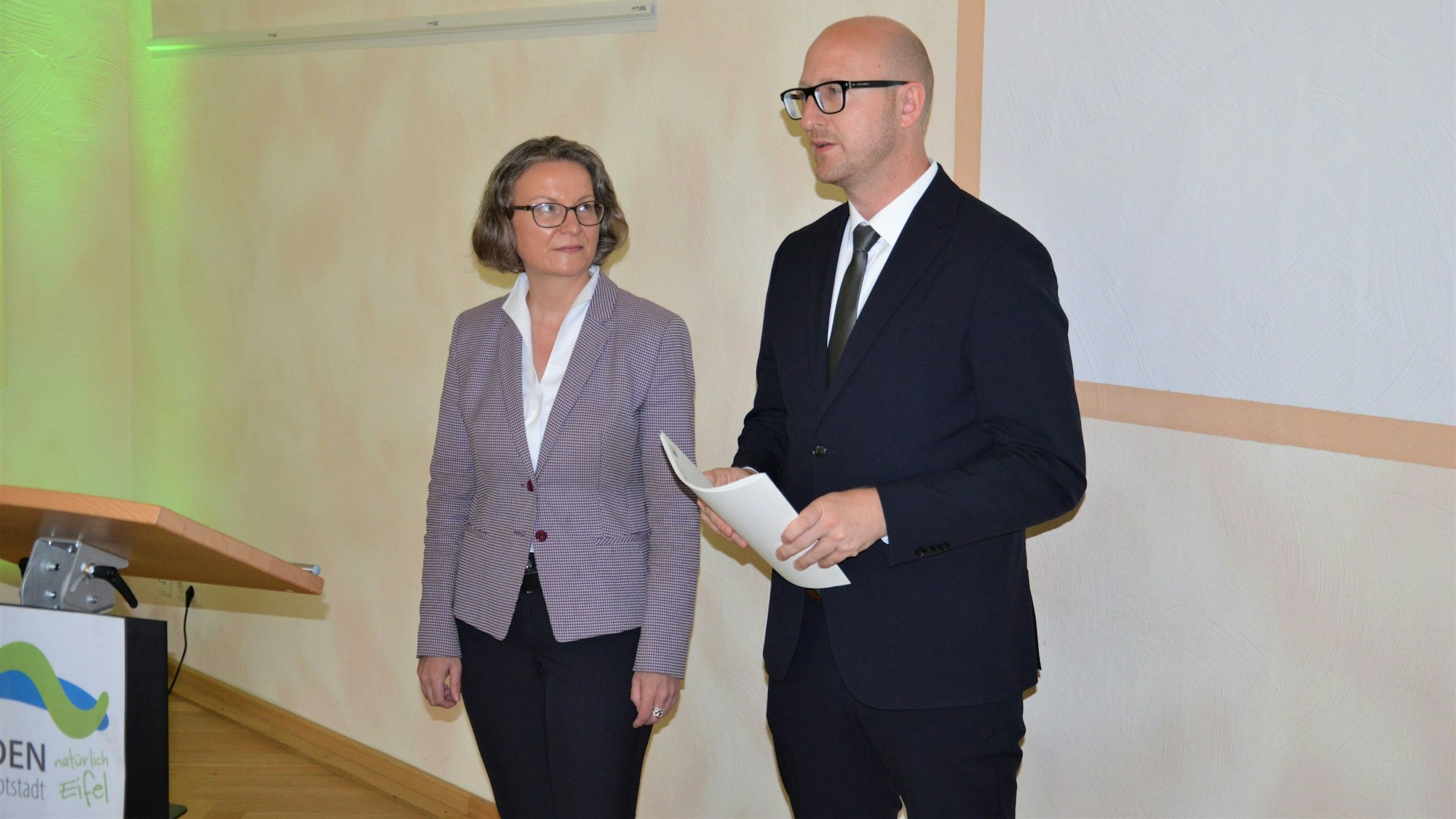 Das Bild zeigt eine Frau und einen Mann, der ein Papier in der Hand hält.