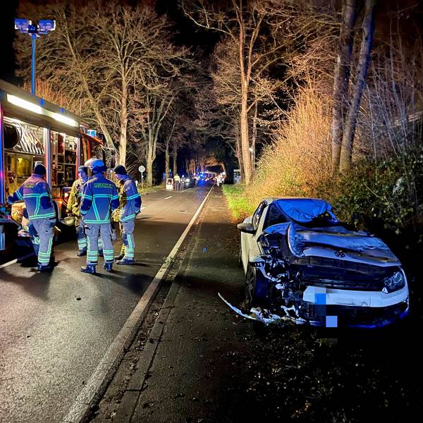 Ein demolierter VW Scirocco steht am Straßenrand. Mehrere Feuerwehrleute sind an der Unfallstelle auf der Wahnbachtalstraße im Much.