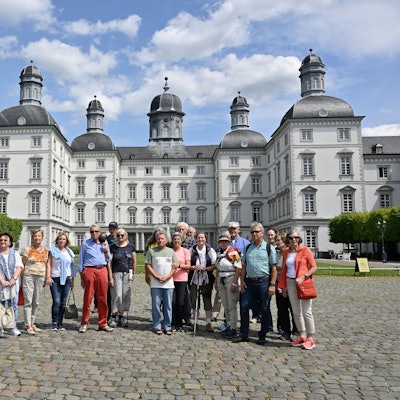 Eine Wandergruppe steht mit Naturparkführer und Redaktionsleiter Guido Wagner im Hof von Schloss Bensberg.