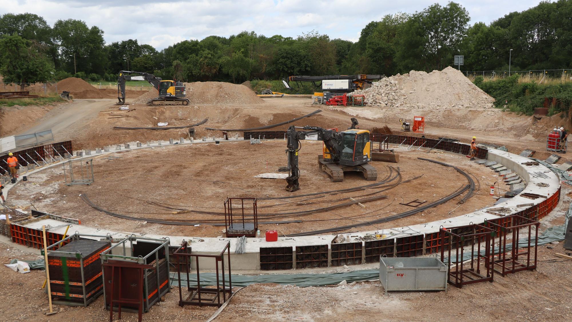 Das Bild zeigt die Baustelle des Wasserauffangbeckens. In der Mitte steht ein Bagger.