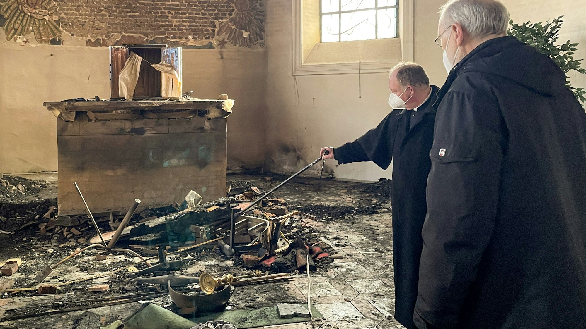 Weihbischof Ansgar Puff (r.) und Dechant Martin Kürten stehen in der zerstörten Pfarrkirche Kreuzerhöhung und betrachten das Ausmaß der Schäden. Für den Brand im Februar vergangenen Jahres muss sich jetzt ein Reichshofer vor dem Landgericht in Koblenz verantworten.