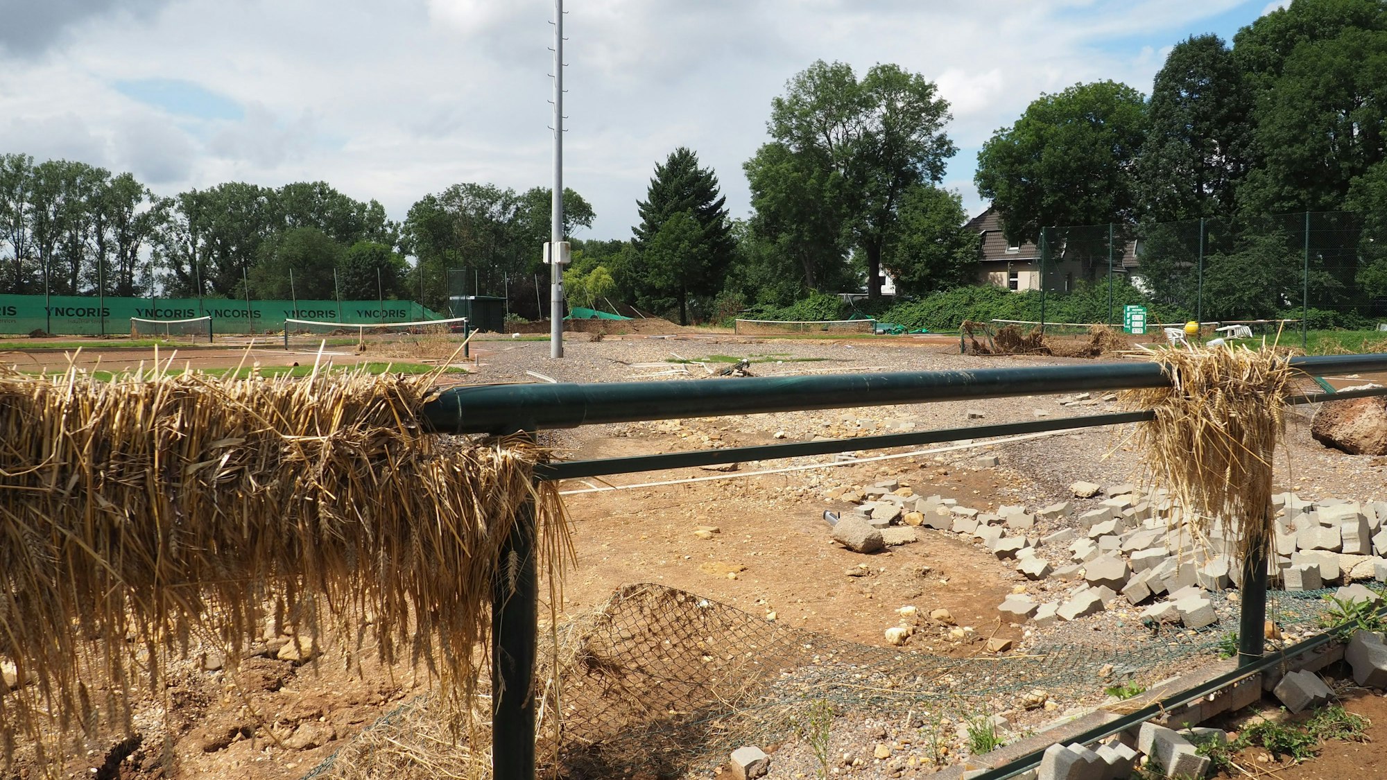 An einem Zaun hängt Treibgut, dahinter sind Trümmer.