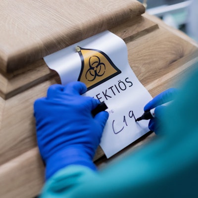 Ein Bestattungsunternehmer schreibt „C19“ auf ein Schild mit dem Hinweis „Infektiös“ auf einen Sarg mit einem Verstorbenen, der an dem Coronavirus gestorben ist.