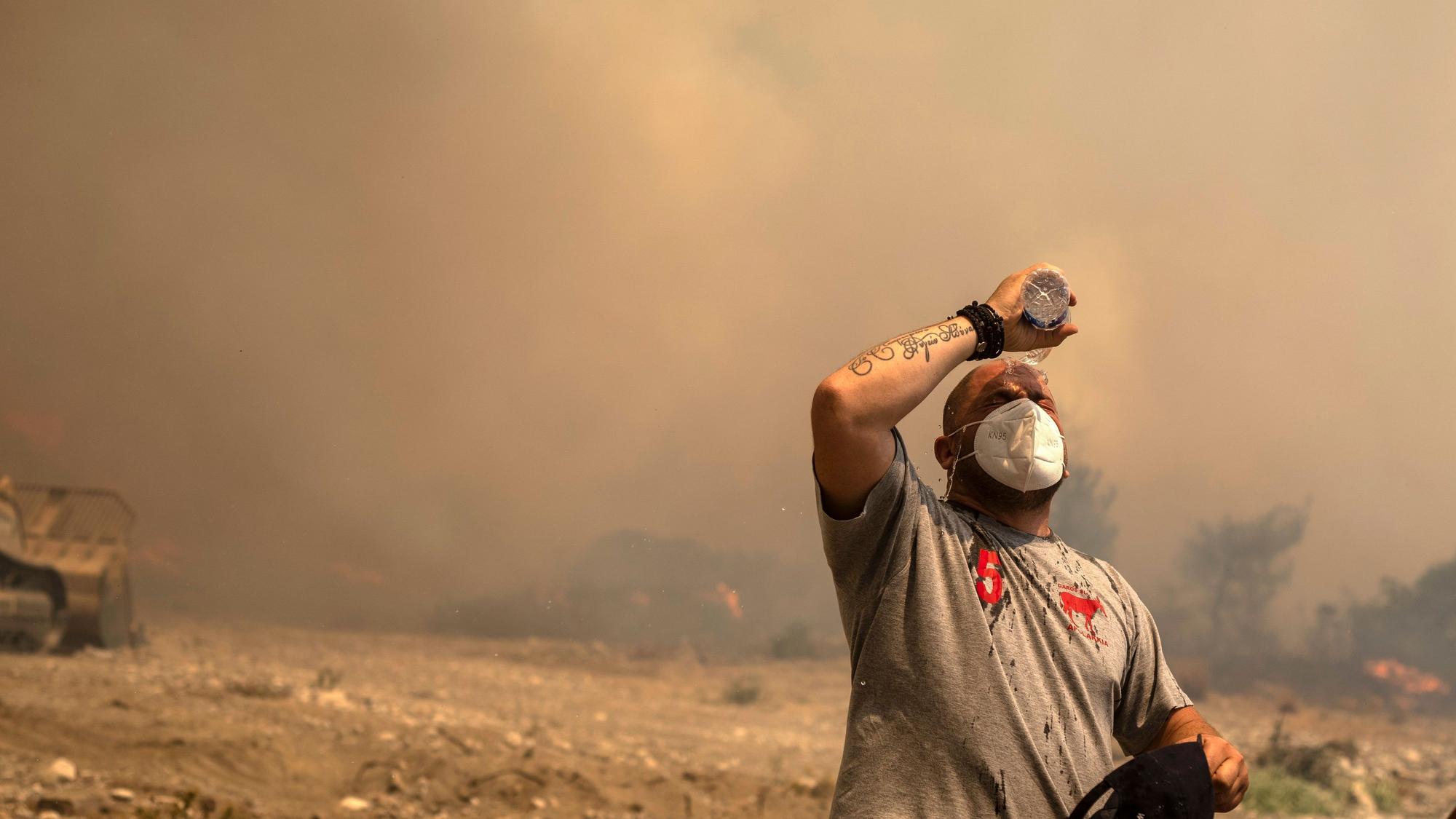 25.07.2023, Griechenland, Rhodos: Ein Freiwilliger Helfer kühlt sich während eines Waldbrandes in der Ortschaft Vati ab. Starke Winde erschweren den Kampf gegen die Waldbrände auf der griechischen Ferieninsel Rhodos. Foto: Petros Giannakouris/AP/dpa +++ dpa-Bildfunk +++
