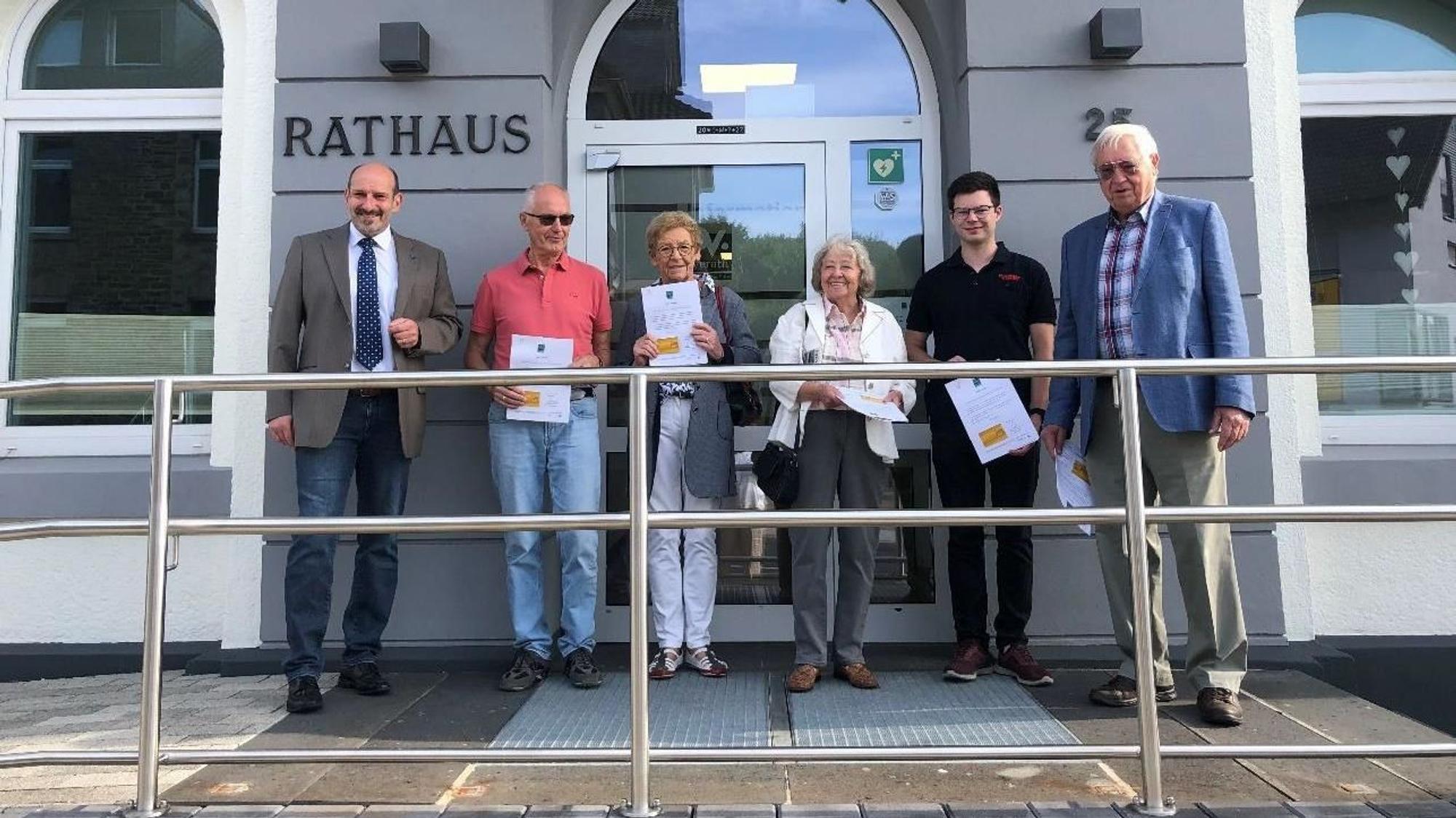 Bürgermeister Christoph Nicodemus (l..) steht mit Overather Bürgerinnen und Bürgern vor dem Rathaus-Eingang.