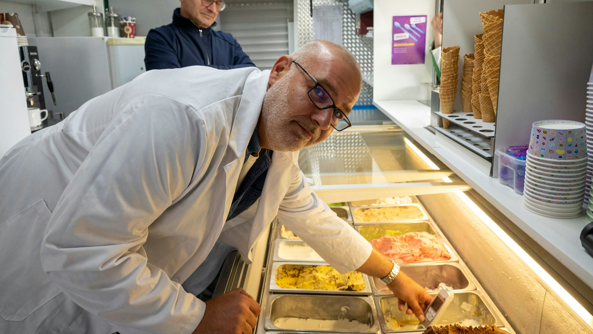 Ein Mann steht in einem Eiswagen und überprüft das Eis und den Laden.