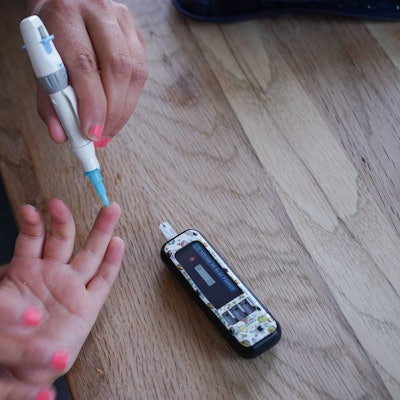 Das Bild zeigt eine Frau, die bei einem Kind einen Blutzuckertest macht.