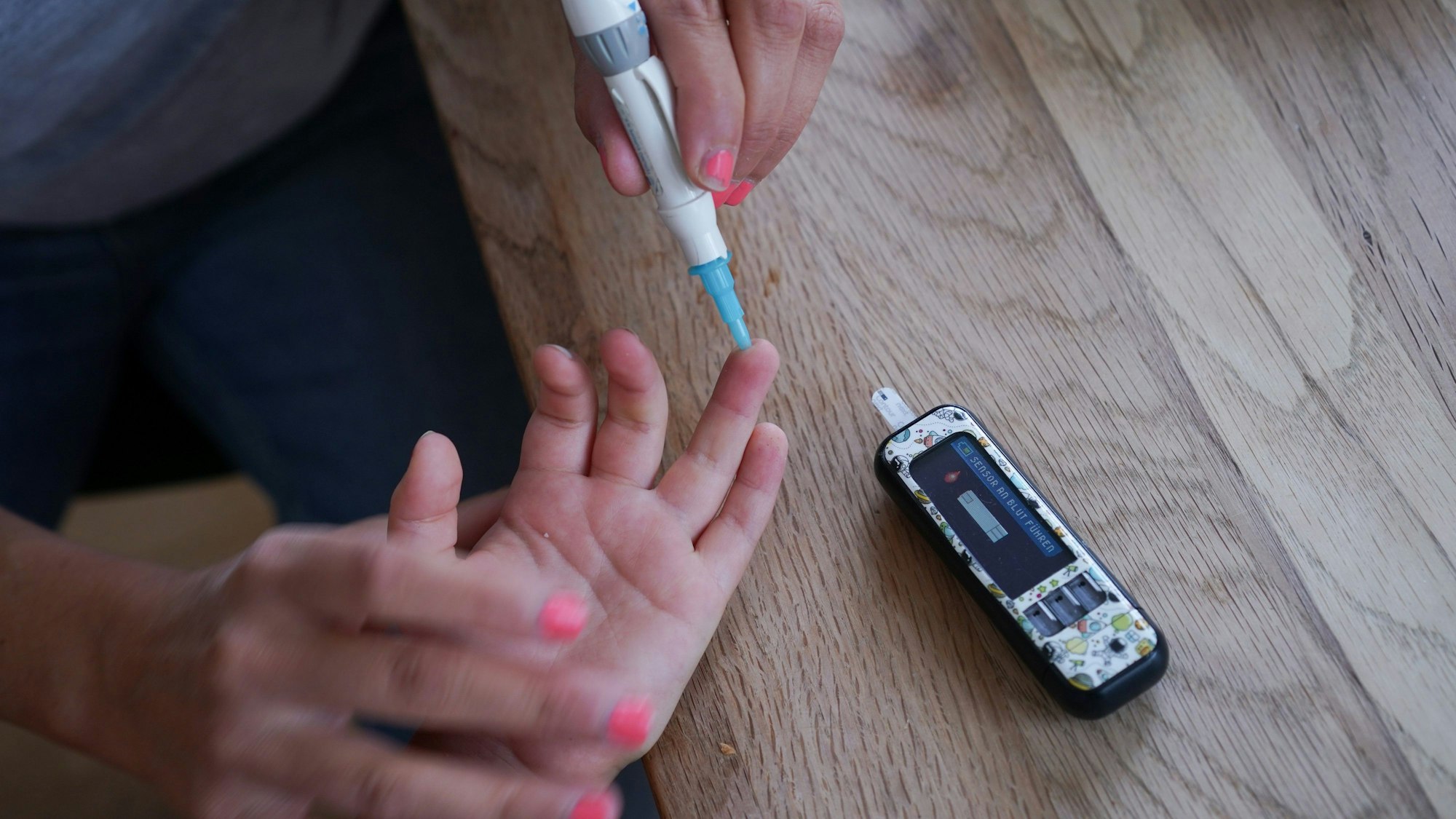 Dem vierjährigen Oskar wird von seiner Mutter der Blutzuckergehalt gemessen.