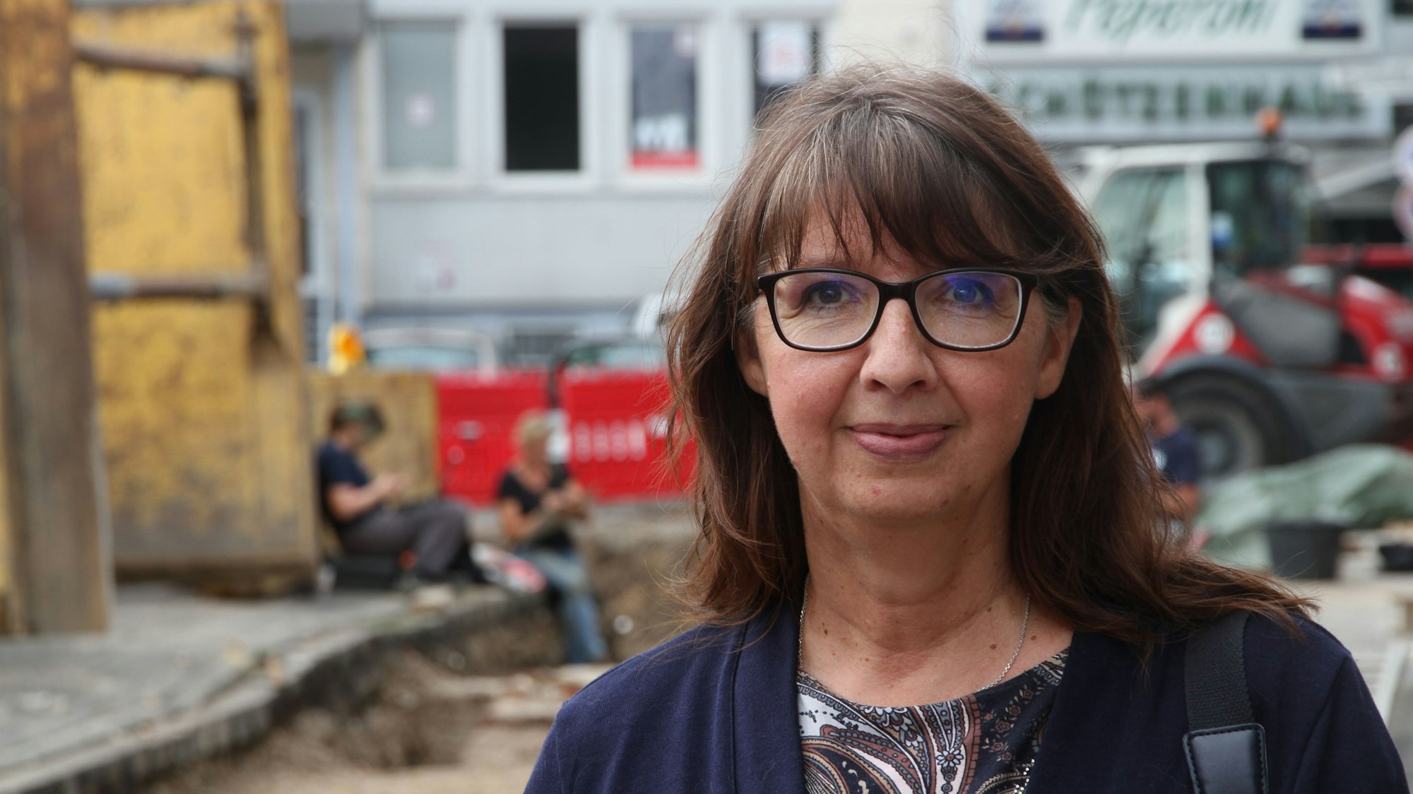 Eine Frau steht vor einer Ausgrabungsstätte.