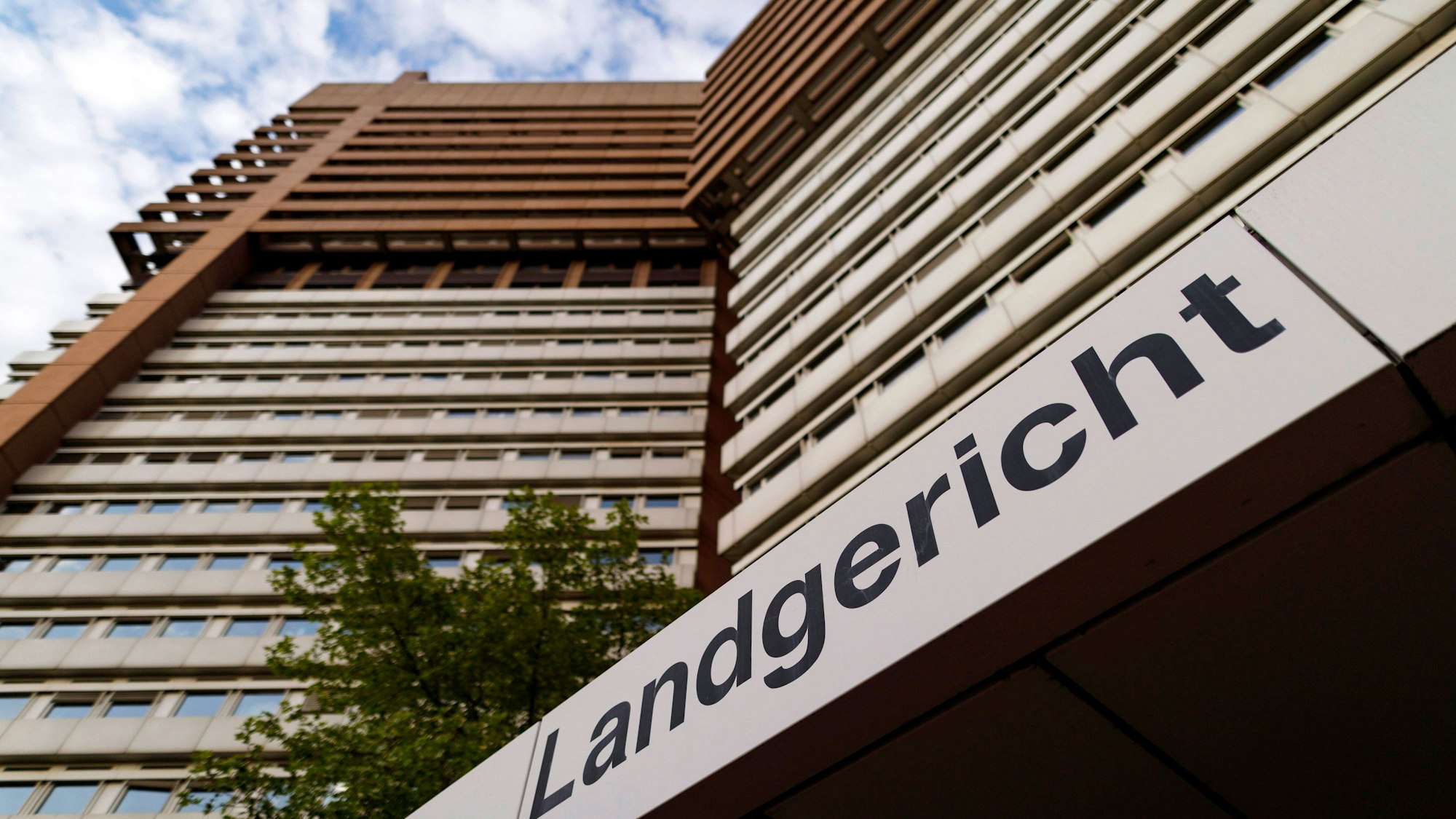 Blick von unten auf das Hochhaus des Justizzentrums in Köln. Im Vordergrund ist der Schriftzug „Landgericht“ zu sehen.