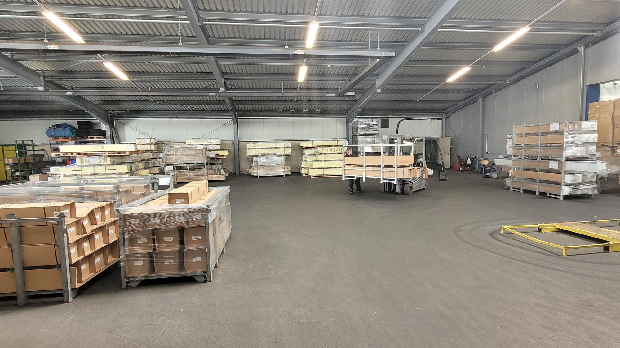 Das Foto zeigt eine große Werkshalle, in der auf Paletten eingepackte Ware zum Versand steht.