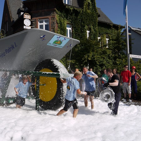 Teilnehmer mit einer Riesenschubkarre auf einem Teppich von Löschschaum