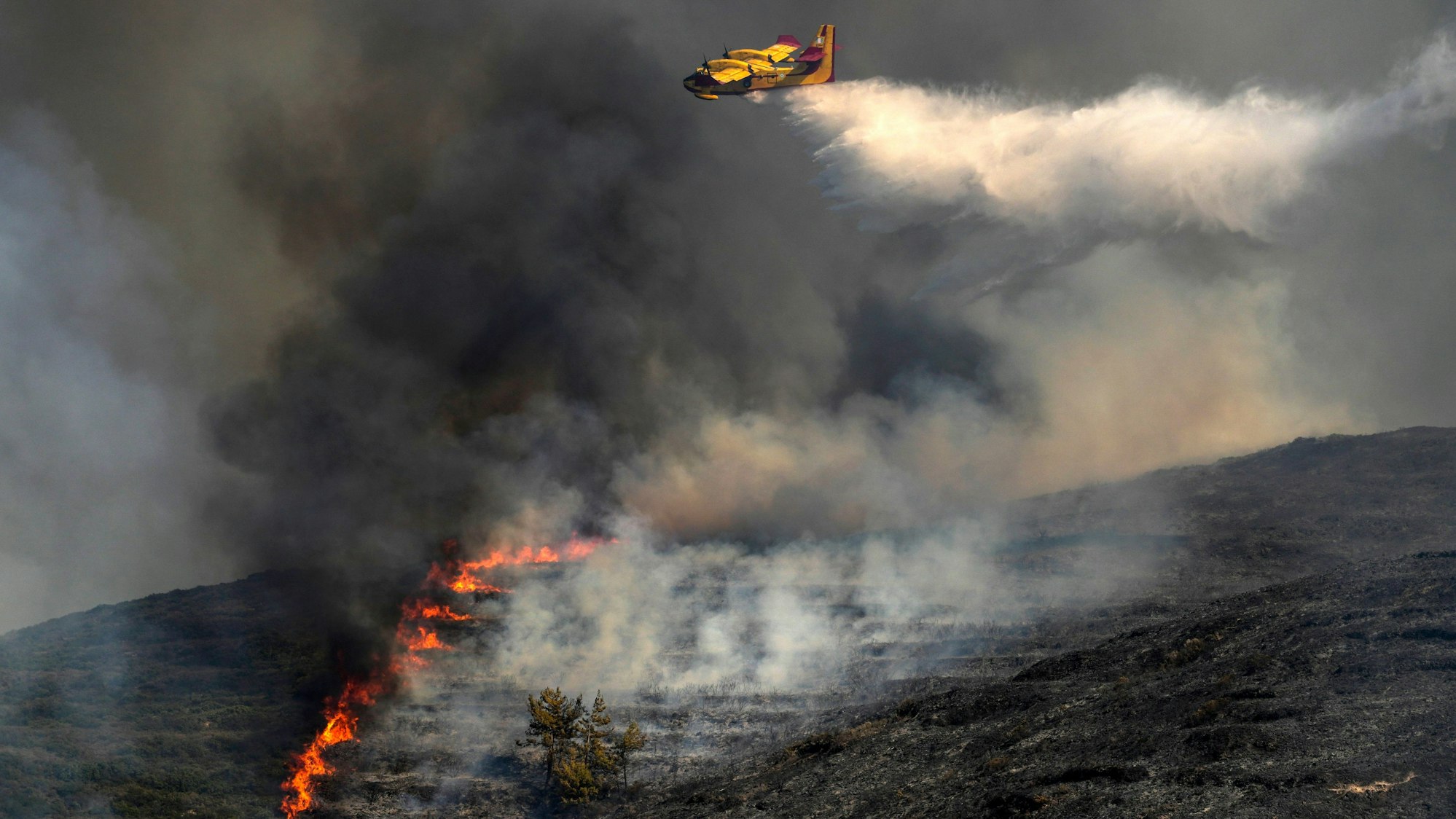 Ein Flugzeug wirft Wasser über einem Waldbrand in dem Dorf Vati auf der Ägäisinsel Rhodos ab.