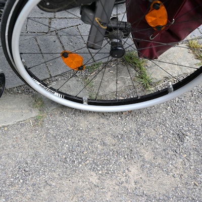 Ein Rollstuhl steht auf einem gepflasterten Weg.