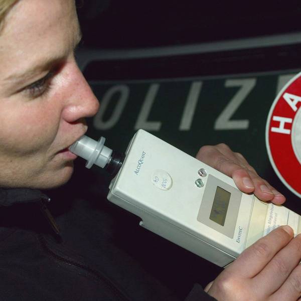 Eine Autofahrerin pustet einer Verkehrskontrolle der Polizei in ein Alkohol-Atemmessgeraet.
