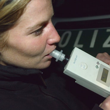 Eine Autofahrerin pustet einer Verkehrskontrolle der Polizei in ein Alkohol-Atemmessgeraet.