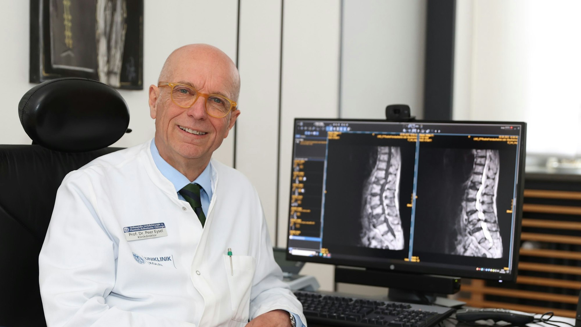 Peer Eysel sitzt vor einem Bildschirm mit Röntgenaufnahmen von einer Wirbelsäuse.