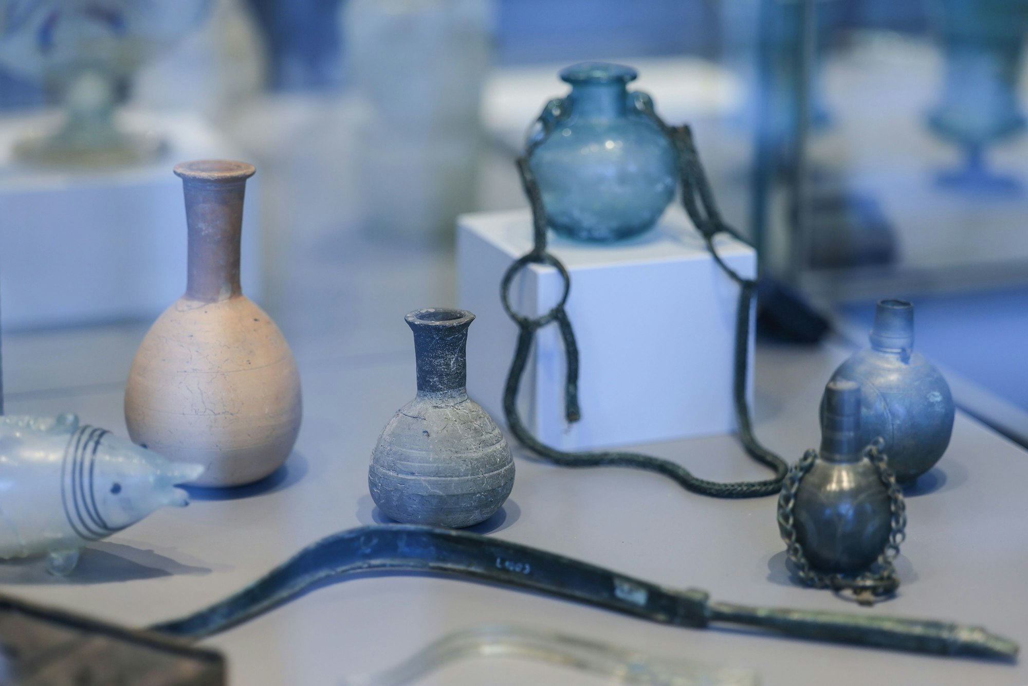 Mehrere historische Gegenstände stehen in einer Vitrine. Darunter alte Parfüm-Flakons und ein Haarausreißer, der an eine Sichel erinnert.