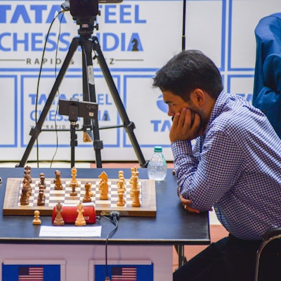 Die Kontrahenten sitzen sich in Denkposen gegenüber, wischen ihnen das Schachbrett. Ein Handy mit Stativ filmt das Brett.