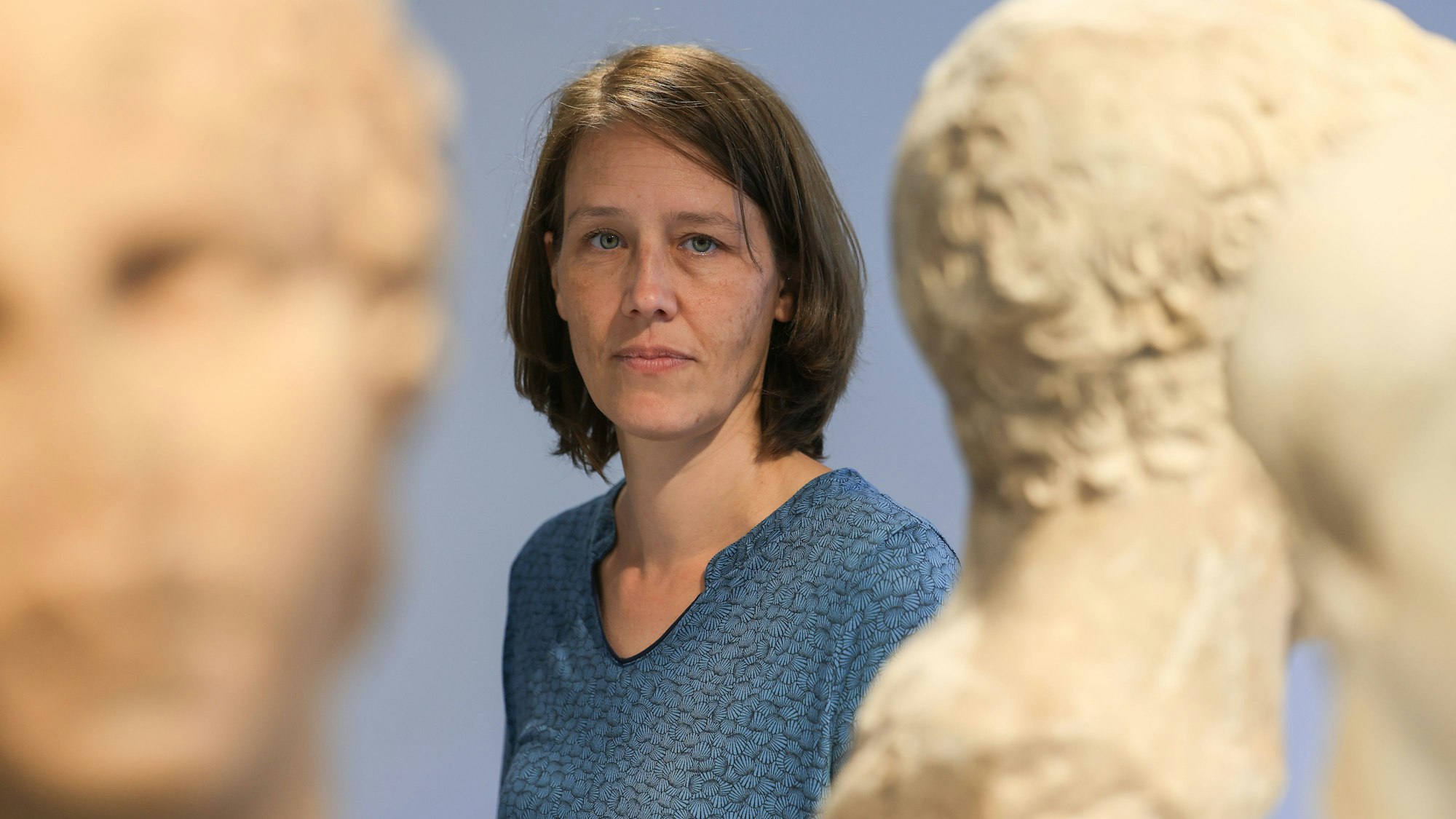 Eine Frau steht zwischen Skulpturen.