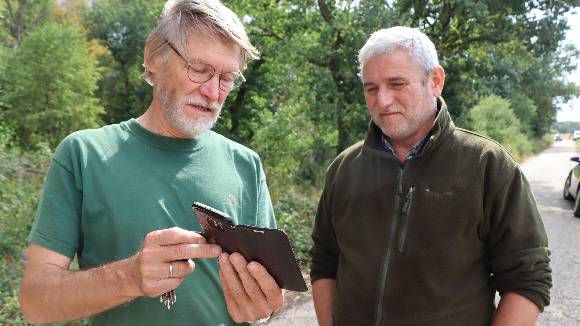 Das Foto zeigt Jagdpächter Wolfgang Curt und Dr. Christian Kohlsdorfer im Gespräch: Sie schauen auf dem Handy, wo die Kitze im Wald stecken könnten.