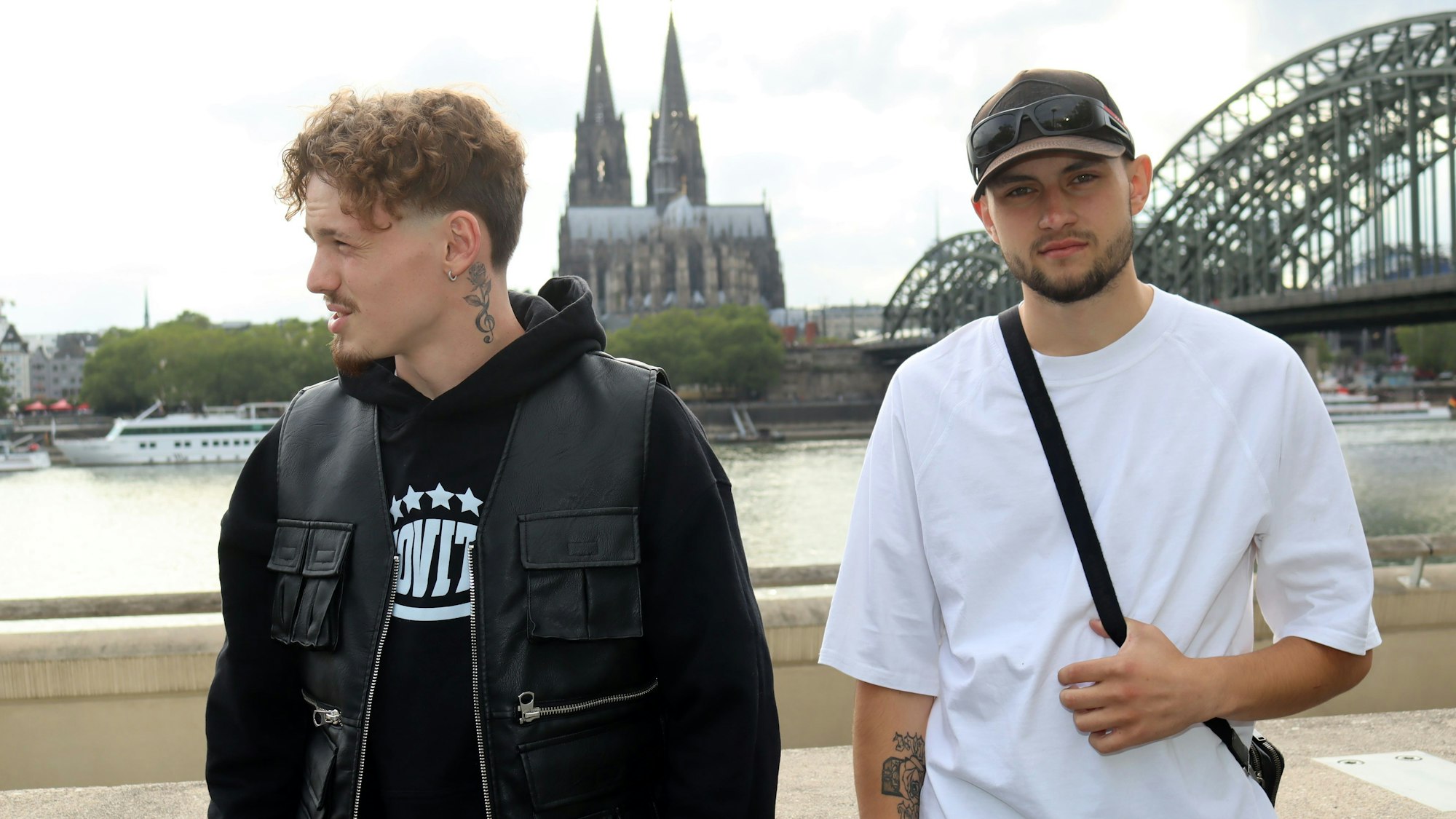 Die Eifeler Musiker Equal (r.) und Liaze posieren am Rhein, im Hintergrund der Kölner Dom.