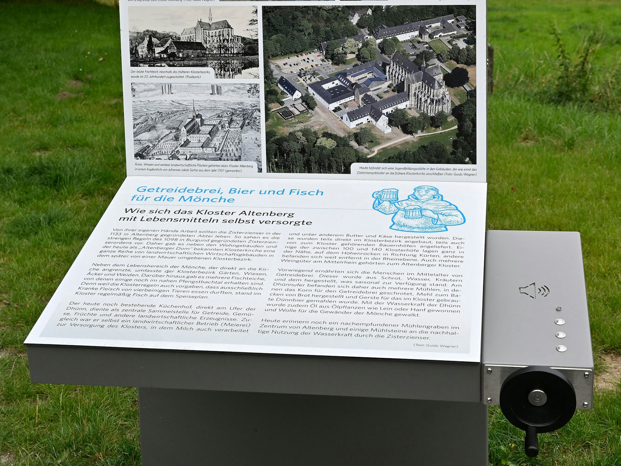 Eine Informationstafel mit Fotos und Texten am Altenberger Dom. Mit einer Kurbel wird ein Tonband bedient.