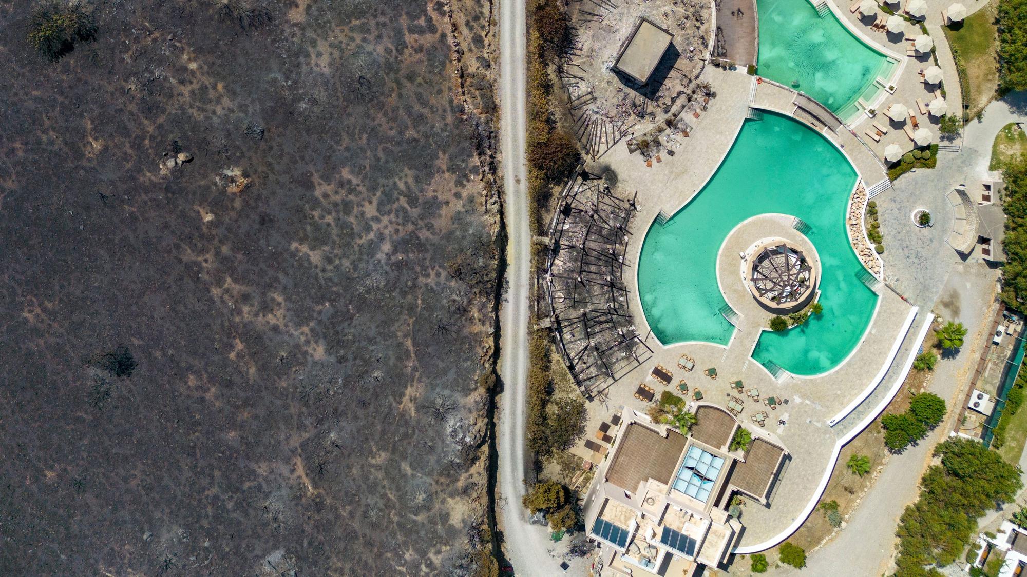 Hinter den Zäunen einer Hotelanlage in Kiotari im Südosten der Ferieninsel Rhodos hat ein Waldbrand die Natur zerstört.
