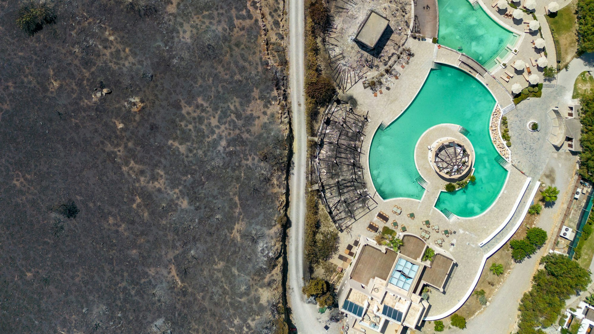 Hinter den Zäunen einer Hotelanlage in Kiotari im Südosten der Ferieninsel Rhodos hat ein Waldbrand die Natur zerstört.