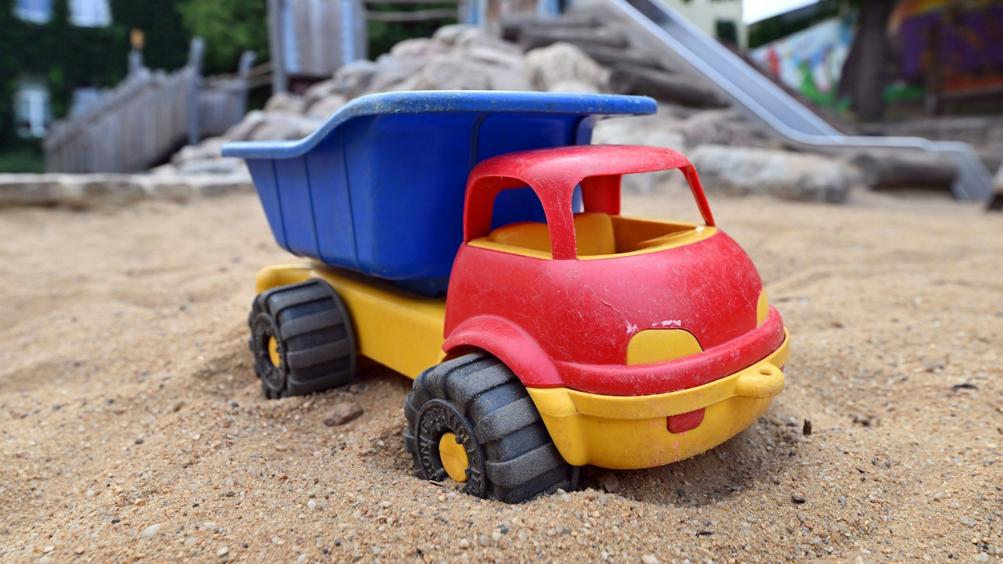 Sandkastenspielzeug steht im Sandkasten des Spielplatzes.