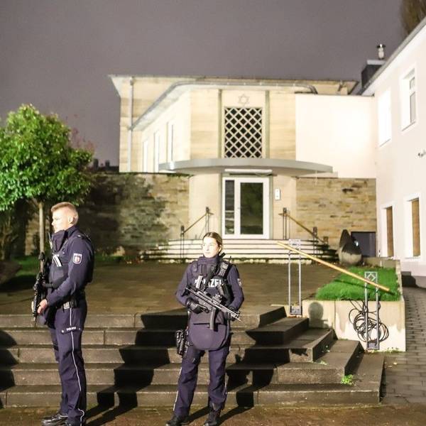 Zwei mit Maschinenpistolen bewaffnete Polizeibeamte stehen vor der Synagoge in der Innenstadt.