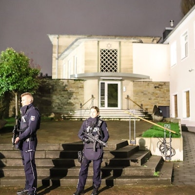 Zwei mit Maschinenpistolen bewaffnete Polizeibeamte stehen vor der Synagoge in der Innenstadt.