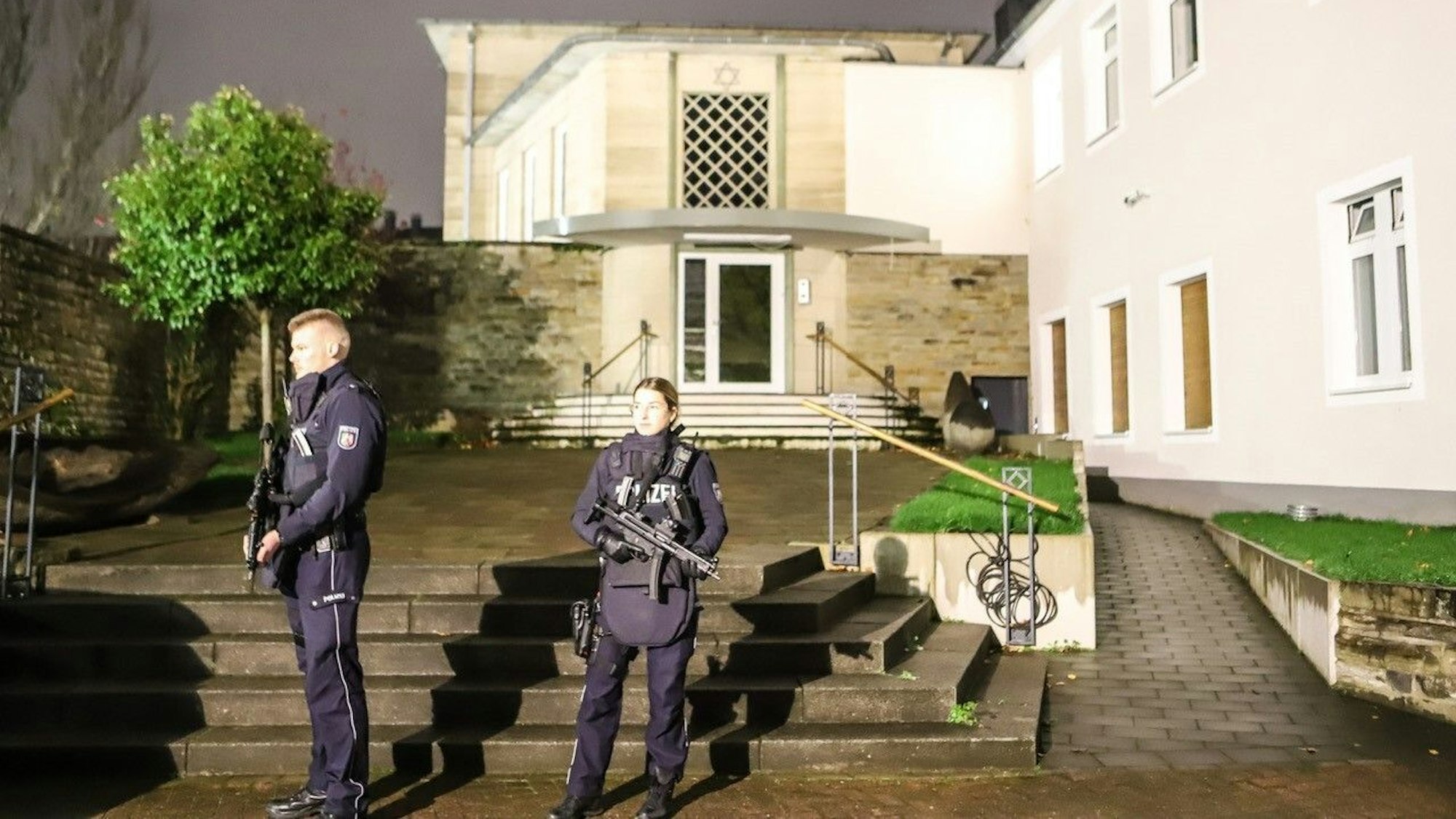 Zwei mit Maschinenpistolen bewaffnete Polizeibeamte stehen vor der Synagoge in der Innenstadt.
