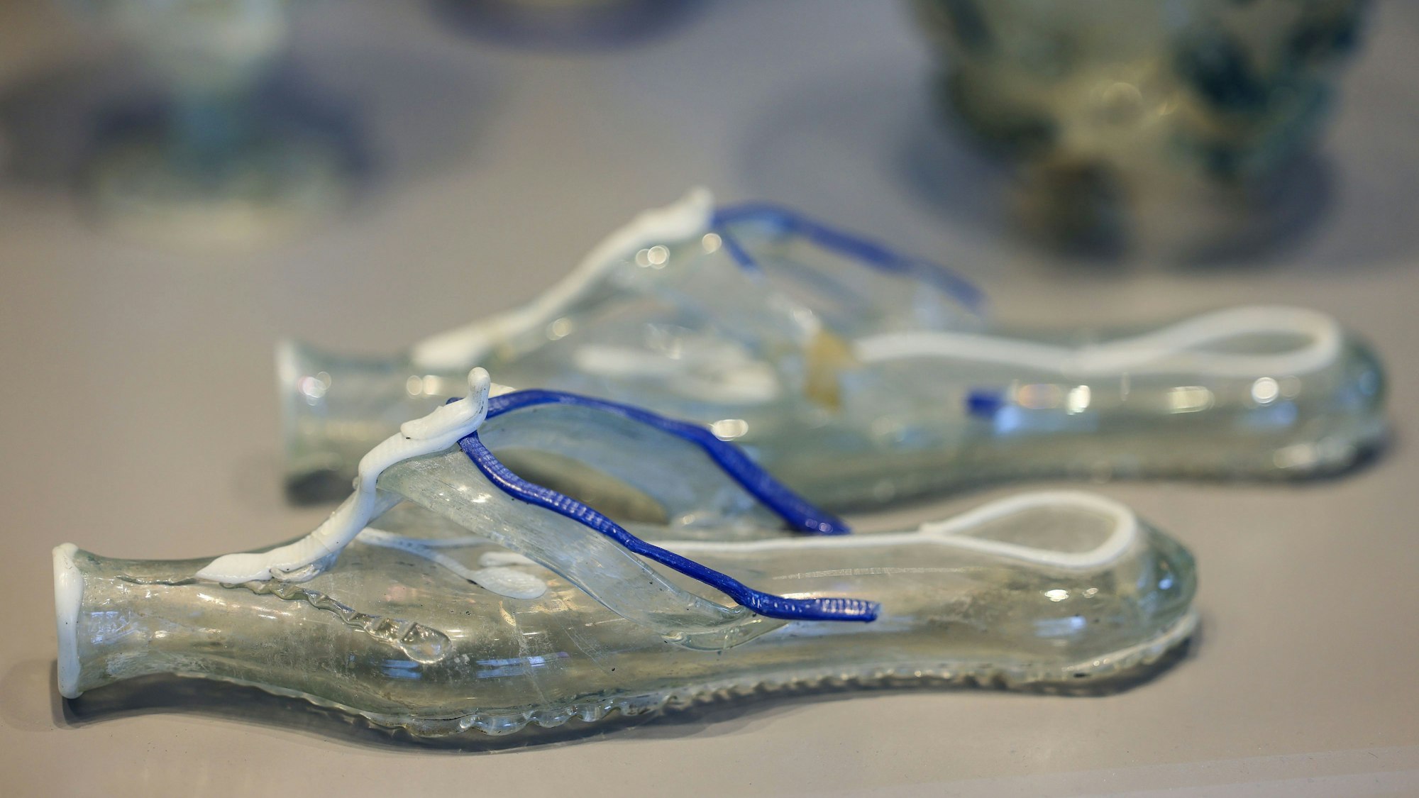 Flip-Flops aus Glas, in deren Sohlen Parfüm eingefüllt werden konnte, liegen in einer Vitrine im Römisch-Germanischen Museum.