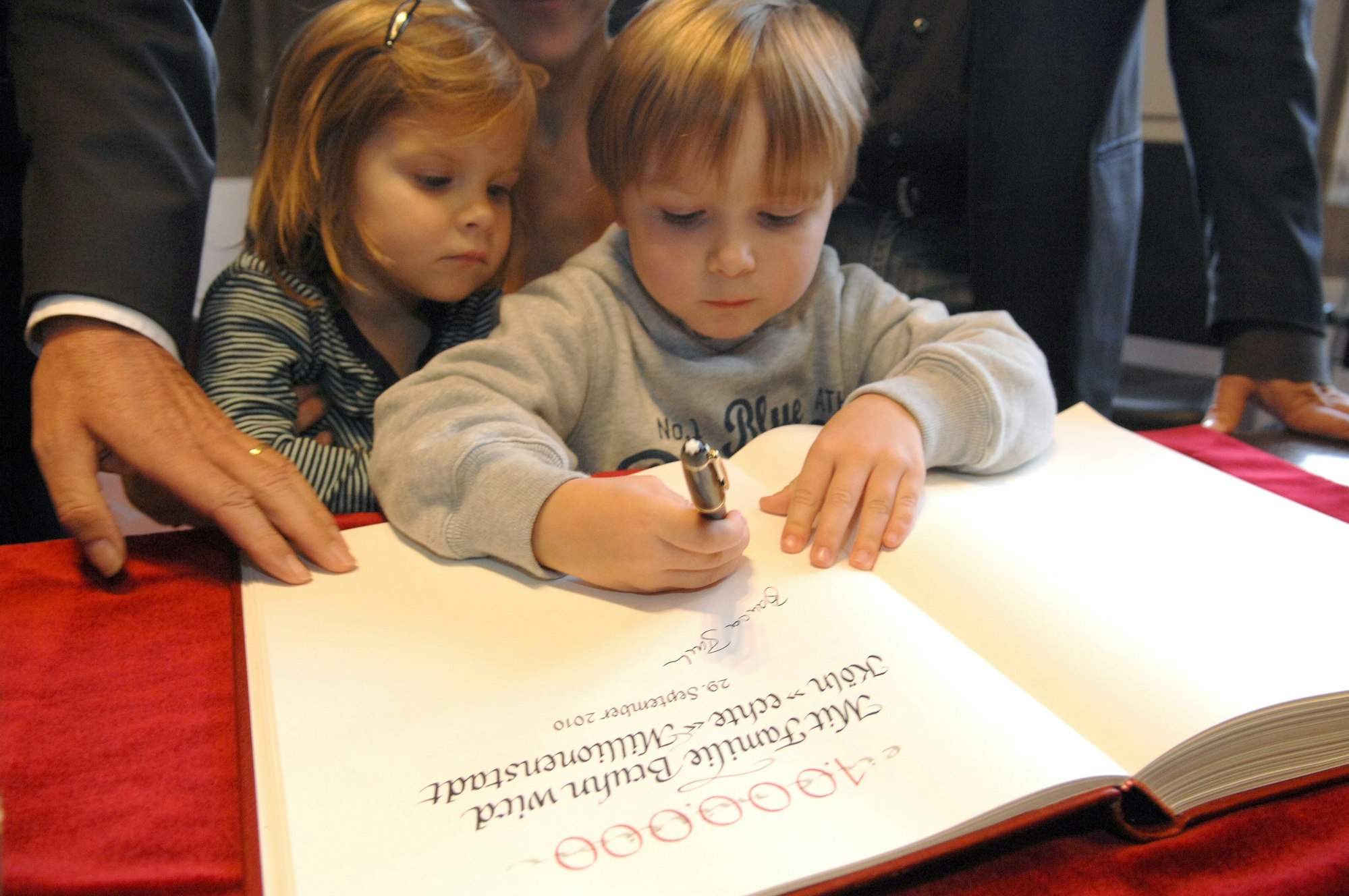 Die Kinder der Millionenfamilie tragen sich ins Goldene Buch der Stadt ein.