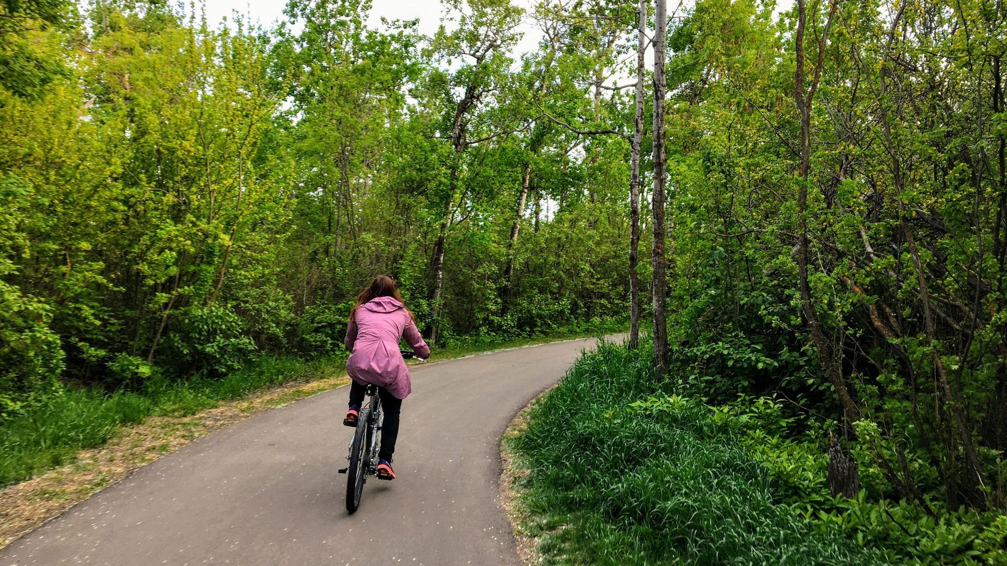 Eine Frau fährt mit dem Fahrrad durch einen Wald