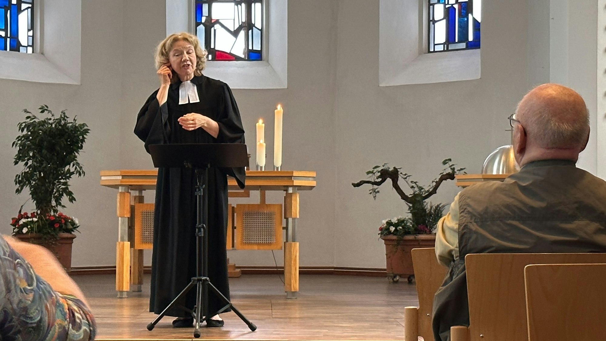 Zu sehen ist eine Pfarrerin in der Kirche, die mit Gebärden predigt.